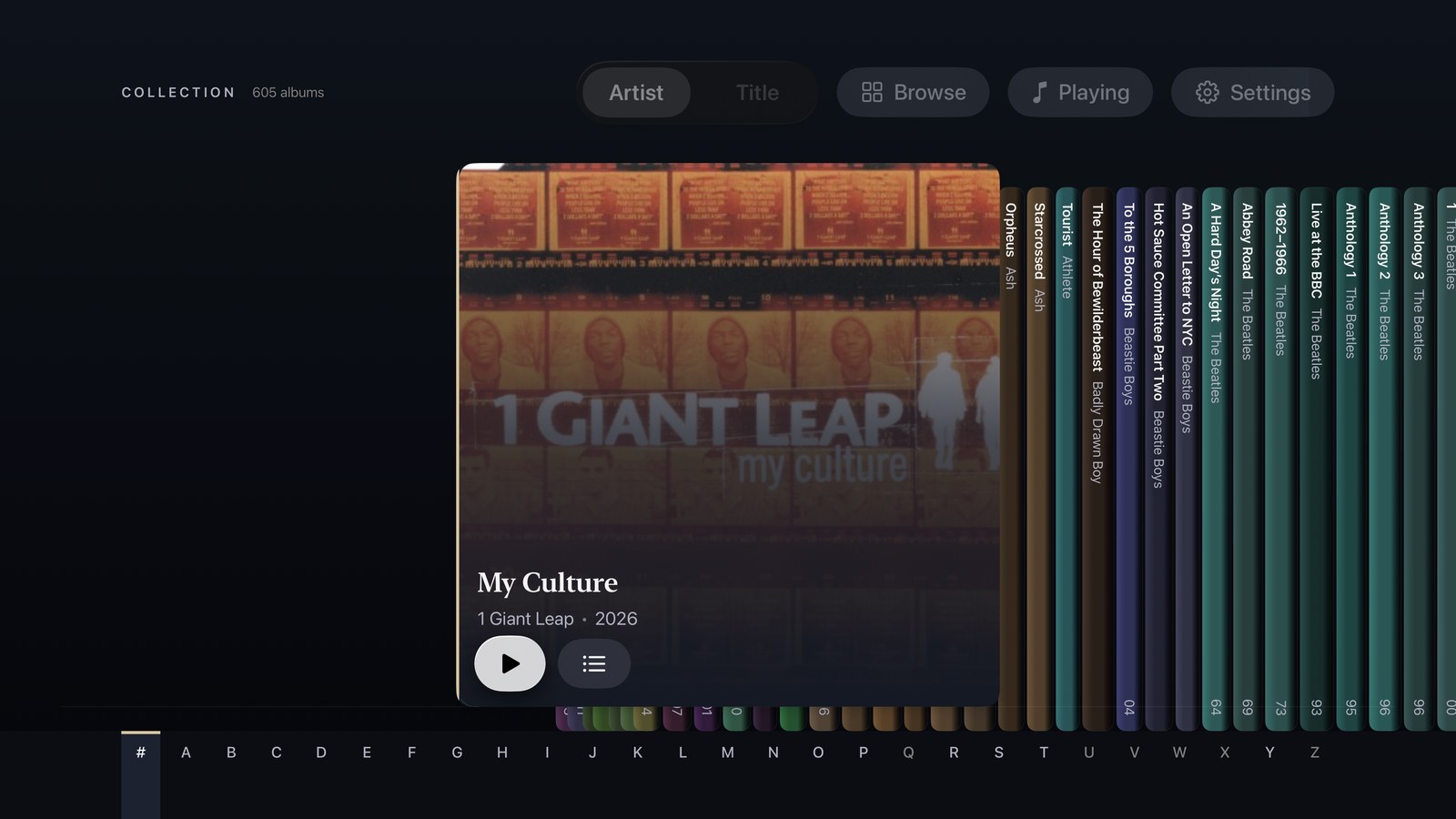 The Shelf view on Apple TV: album spines in a row with one case pulled out to show its artwork, and an A–Z strip along the bottom.